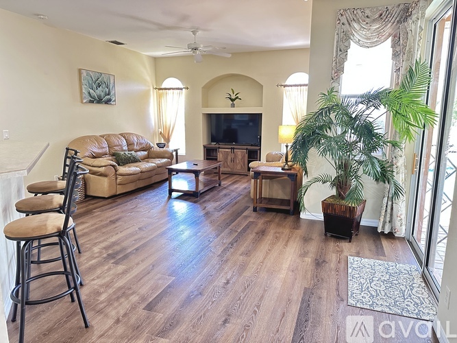 A living room with a brown leather couch and a wooden floor.