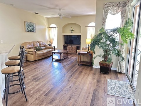 A living room with a brown leather couch and a wooden floor.