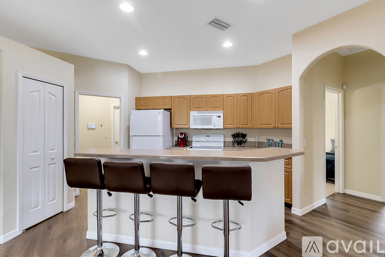 A kitchen with white cabinets and brown bar stools.