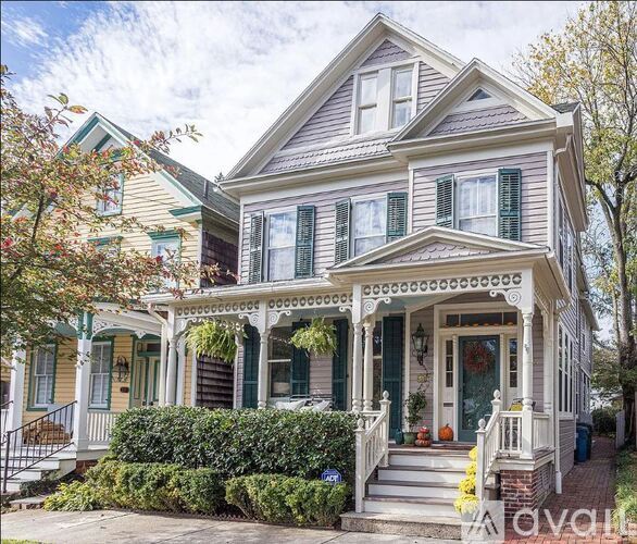 A two-story house with a front porch and green shutters.