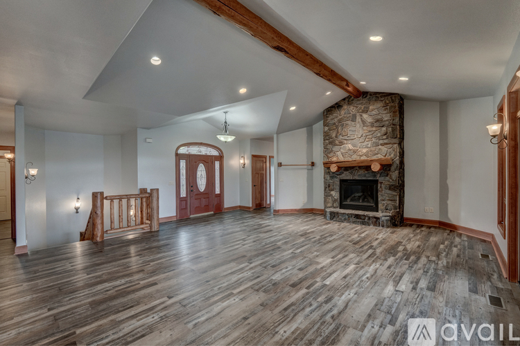 A spacious room with wooden floors and a stone fireplace.