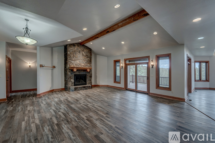 A spacious room with wood flooring and a stone fireplace.