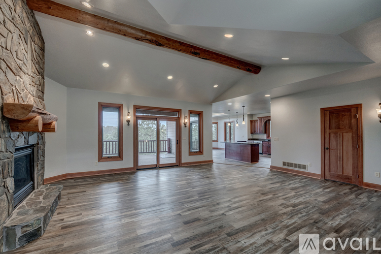 A spacious living room with wood flooring and a stone fireplace.