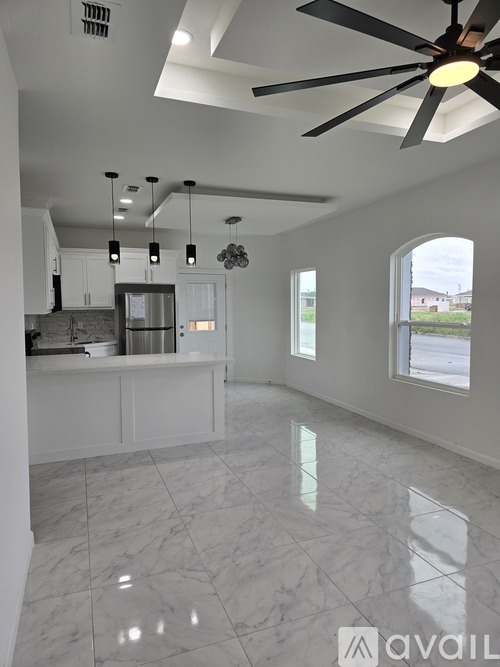 A spacious kitchen with a marble floor and a ceiling fan.