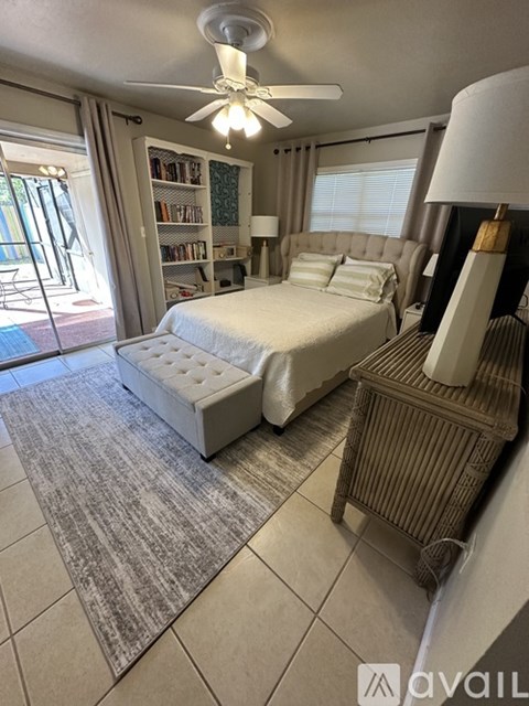 A bedroom with a large bed, a ceiling fan, and a bookshelf.
