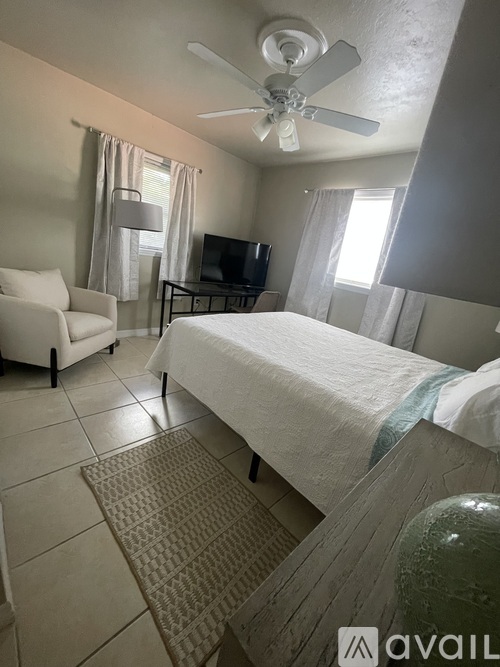 A bedroom with a bed, a chair, and a ceiling fan.