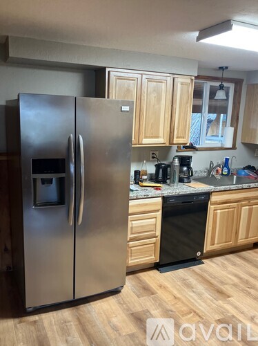 A kitchen with a stainless steel refrigerator and wooden cabinets.