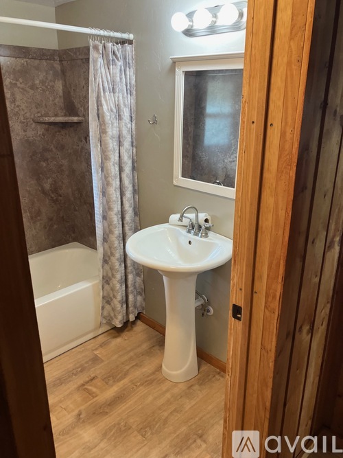 A bathroom with a white pedestal sink and a shower with a brown curtain.