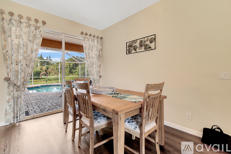 A dining room with a table and chairs and a view of a pool through a sliding glass door.