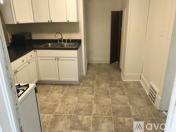 A kitchen with white cabinets and a tiled floor.