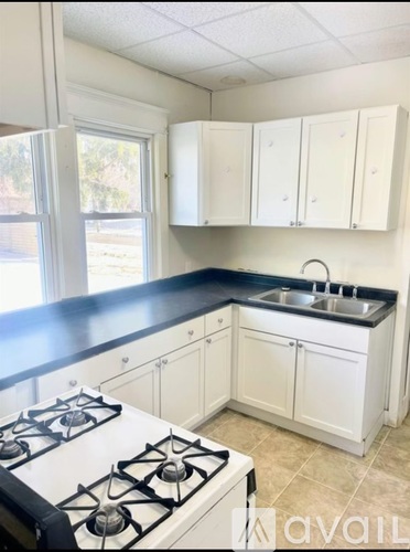 A kitchen with white cabinets and a black countertop.