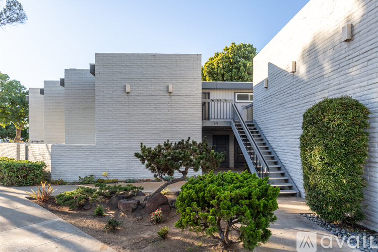 A white building with a tree in front of it.