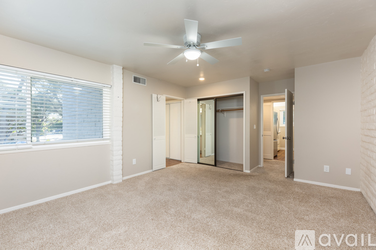 A spacious room with a ceiling fan and a window with blinds.
