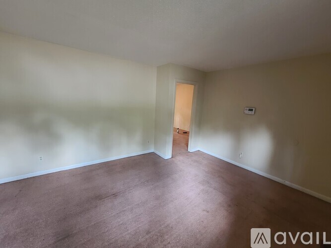 A room with a brown carpet and a door at the end.