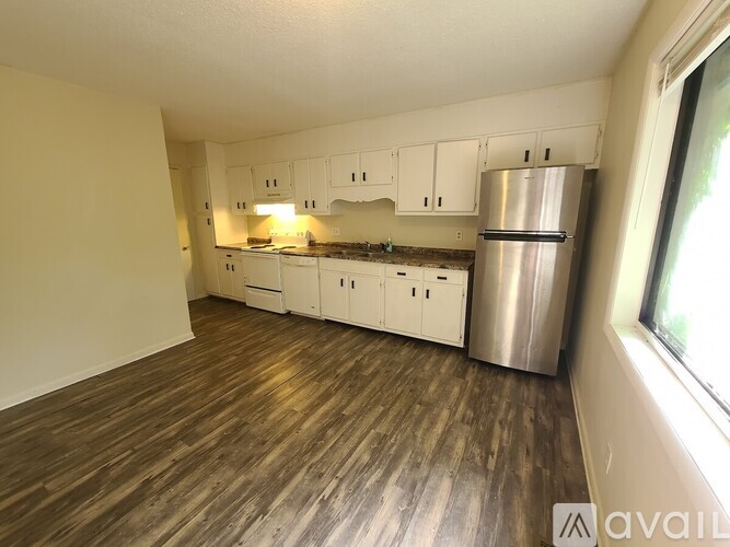 A kitchen with white cabinets and a wooden floor.