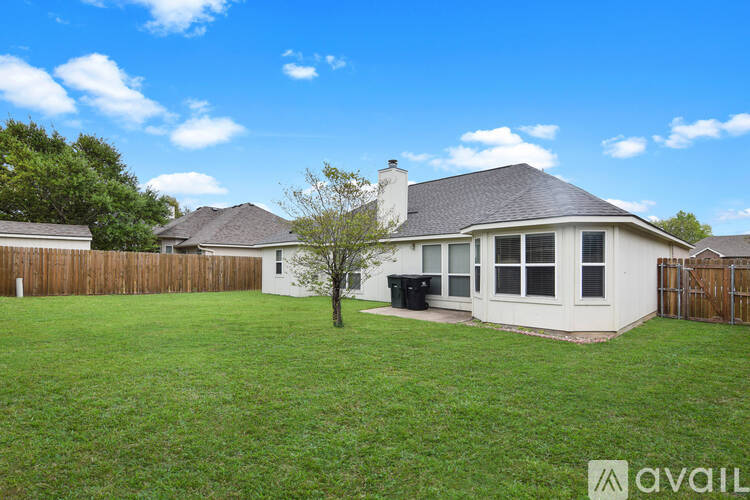 A house with a white exterior and a black trash bin in the yard.