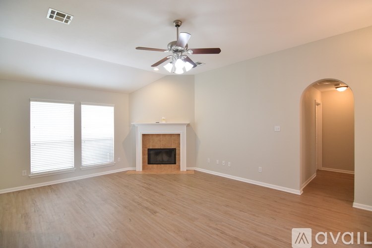A spacious room with a fireplace and a ceiling fan.