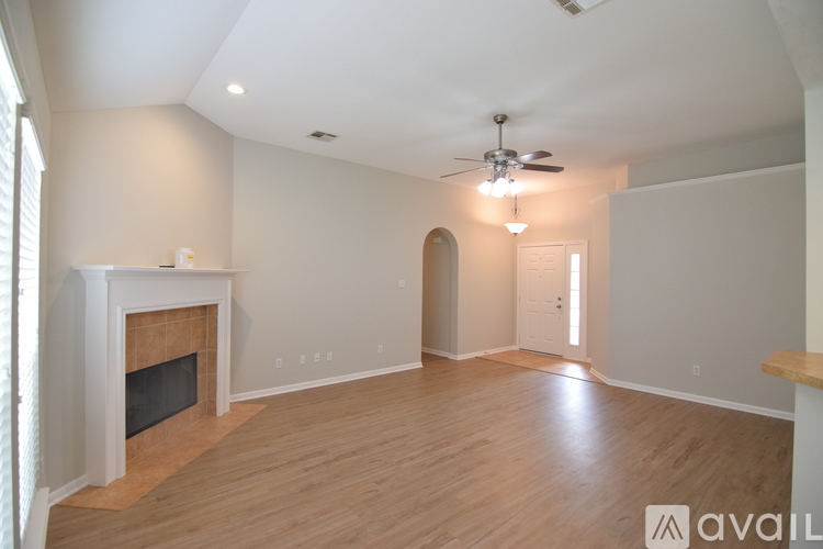 A spacious living room with a fireplace and a ceiling fan.
