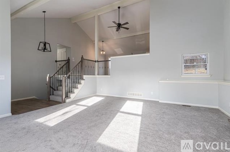 A spacious room with a staircase and a ceiling fan.