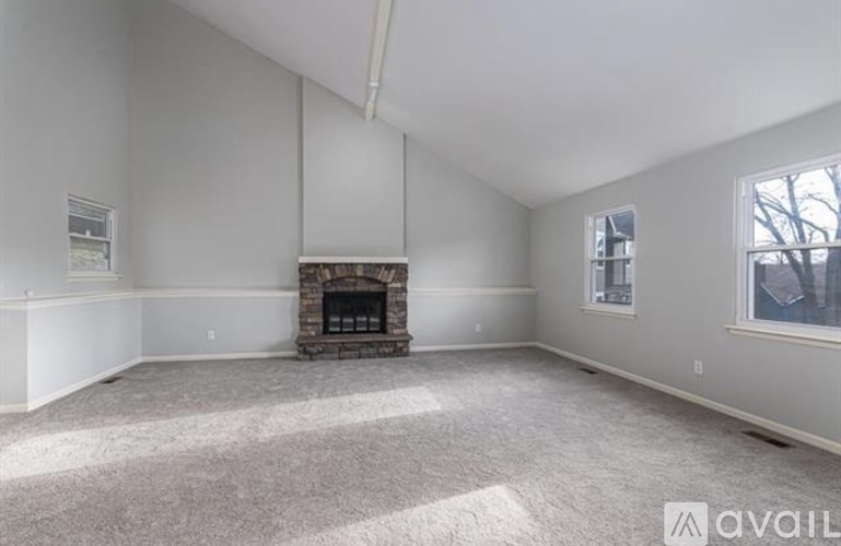 A spacious room with a fireplace and carpeted floor.