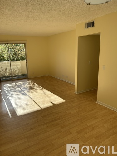 A room with wooden flooring and a sliding glass door.