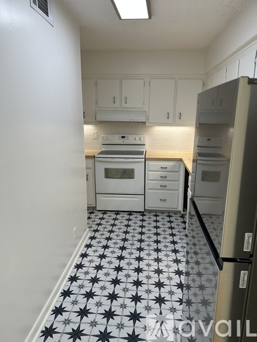A kitchen with white cabinets and a black and white floor.