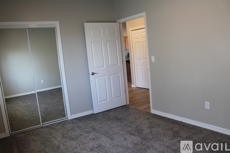 A room with a white door and a carpeted floor.
