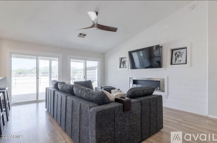 A living room with a grey couch and a television on the wall.