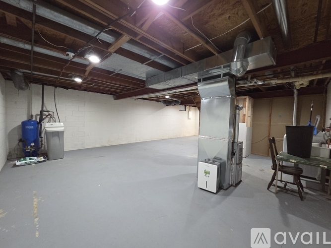 A spacious room with a refrigerator, a chair, and a table.