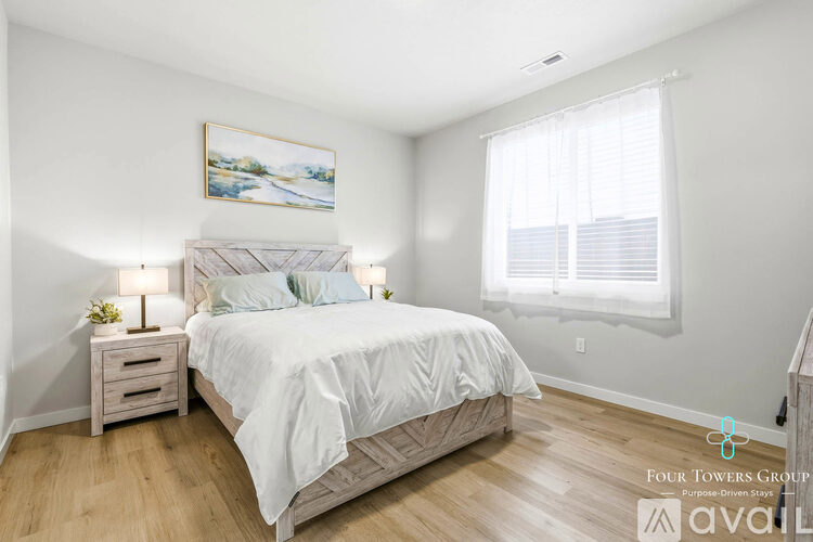 A bedroom with a large bed, a nightstand with a lamp, and a painting on the wall.