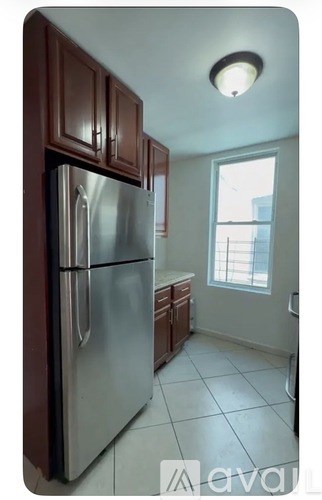 A kitchen with a stainless steel refrigerator and wooden cabinets.