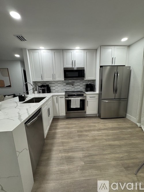 A kitchen with white cabinets and a refrigerator.