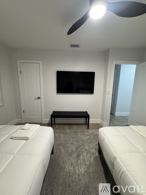 A bedroom with two beds and a flat screen TV mounted on the wall.