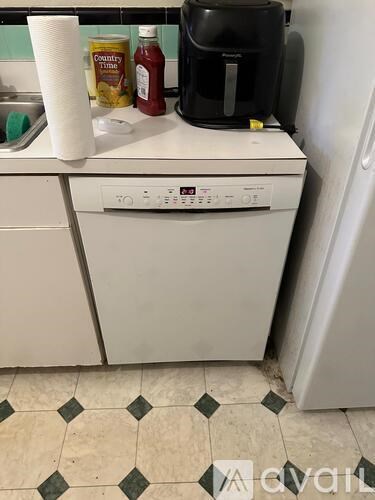 A white dishwasher is in a kitchen next to a coffee maker.