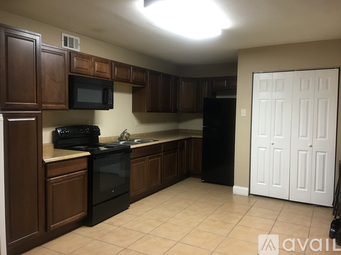 A kitchen with brown cabinets and black appliances.