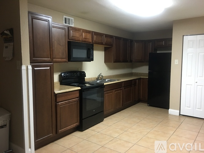 A kitchen with brown cabinets and black appliances.