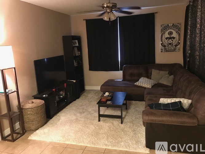A living room with a brown couch, a black entertainment center, and a ceiling fan.