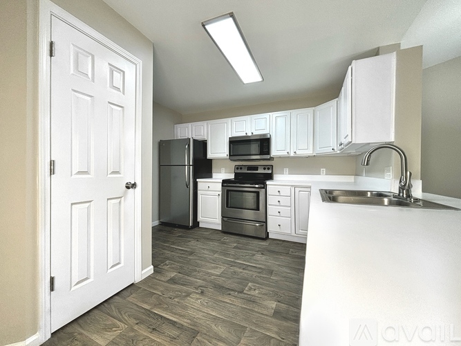 A kitchen with white cabinets and a white door.