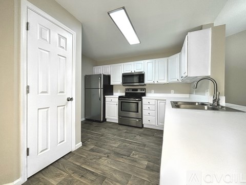 A kitchen with white cabinets and a white door.