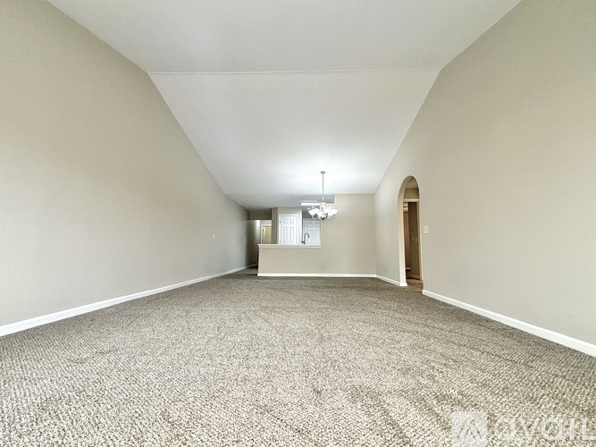 A spacious room with a carpeted floor and a door on the right side.
