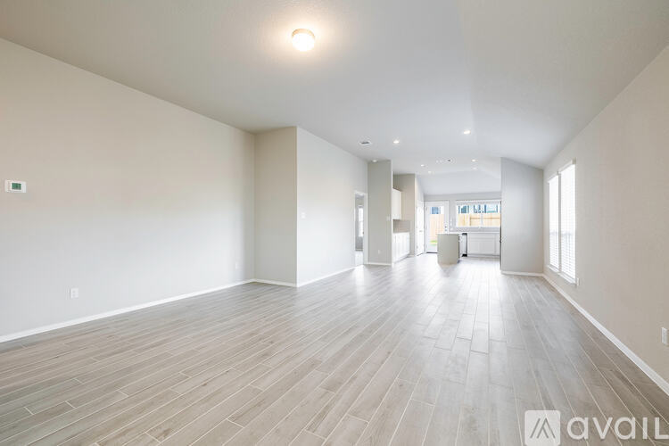 A spacious room with wooden flooring and white walls.