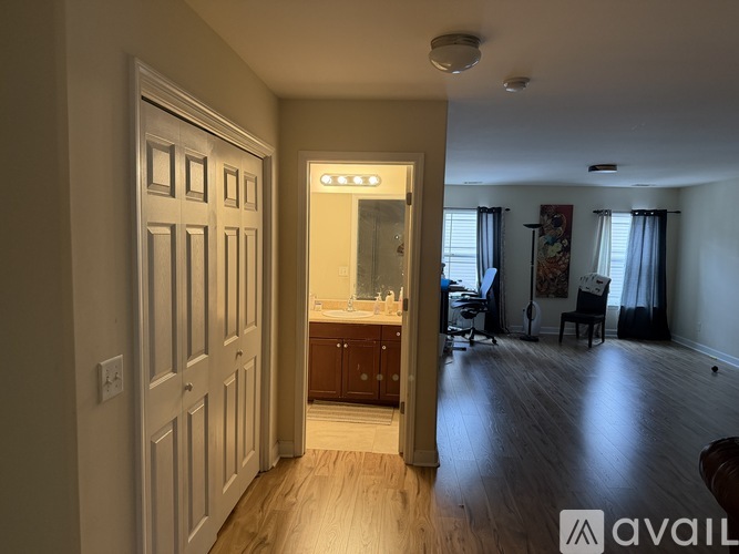 A spacious room with wooden floors and a large mirror on the wall.