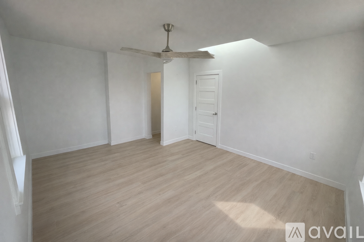 A room with a ceiling fan and light, and a door.