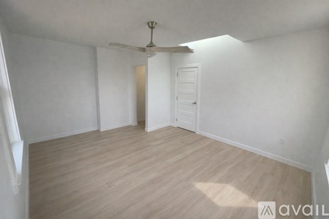 A room with a ceiling fan and light, and a door.