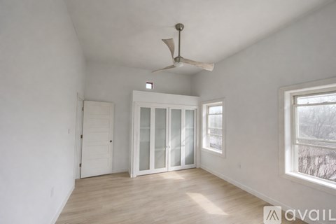 A room with a fan, a window, and a door.