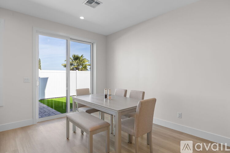 A dining room with a table and chairs and a window overlooking a lawn.