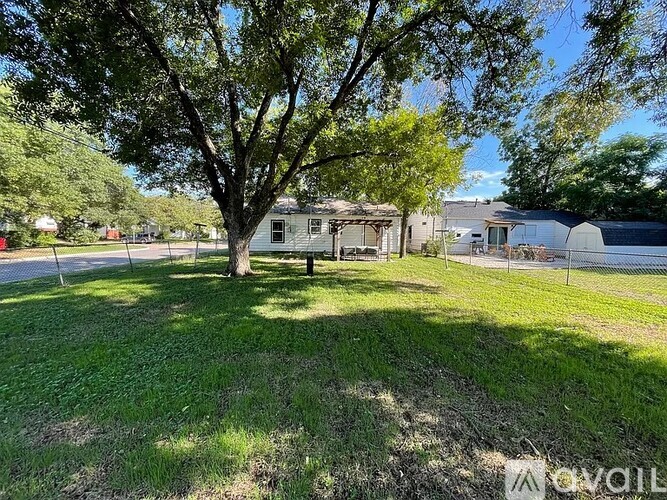 A tree in a grassy area with a house in the background.