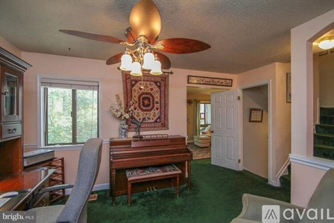 A living room with a fan and a rug hanging on the wall.
