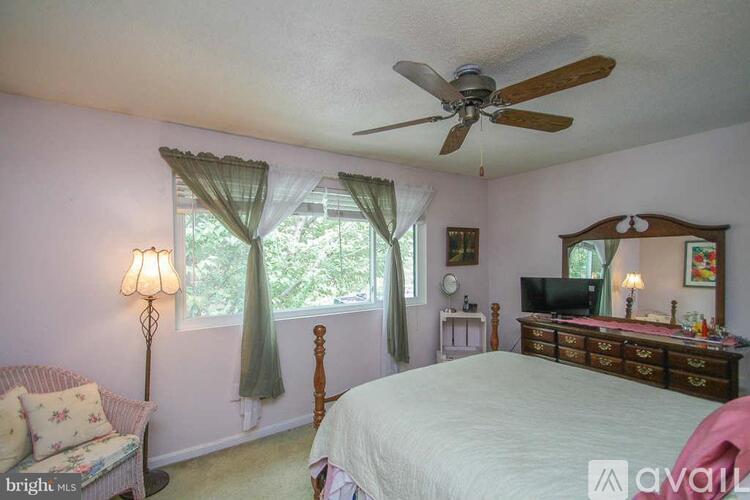 A bedroom with a bed, dresser, and window with curtains.