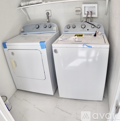 Two white washing machines are taped up and sitting in a small room.